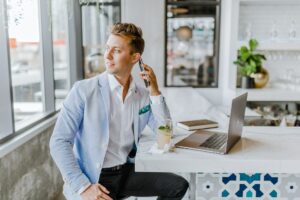 man wearing corporate attire sitting and holding phone